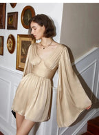 Woman wearing a beige dress in a room with decorative wall plates.