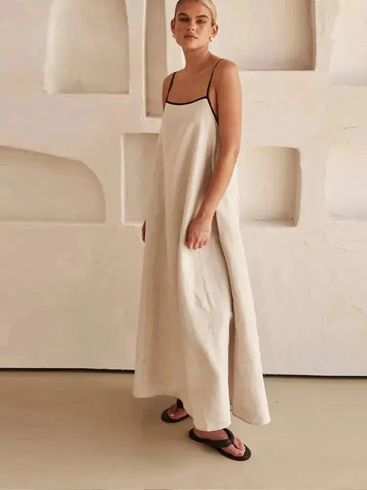 Woman in a long, light-colored dress standing against a neutral background.