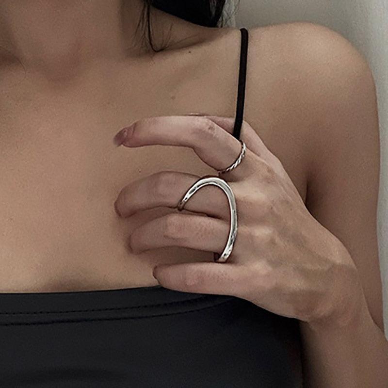 A person wearing a silver-colored ring on their finger, with the rest of their hand and the ring's band visible.