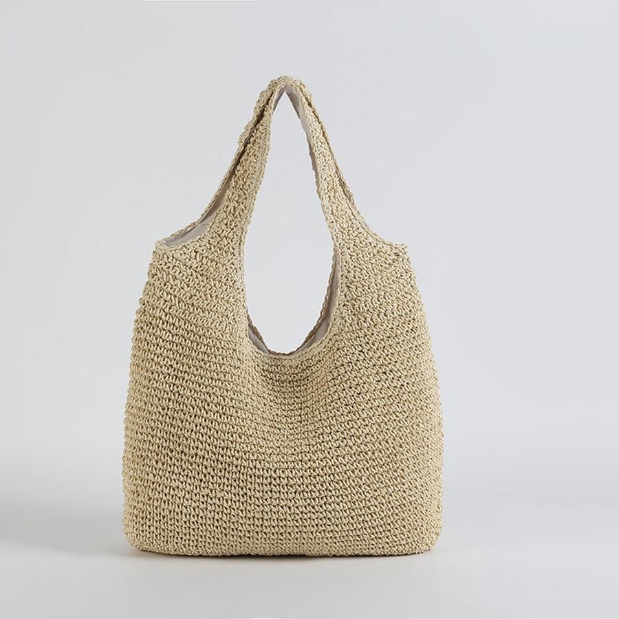 A beige straw handbag with a solid pattern, featuring two handles and a zipper closure at the top.